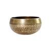 A small handcrafted copper singing bowl held in a person's palm showing etched details