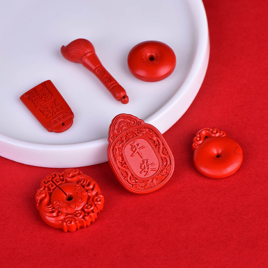 Assortment of carved red cinnabar charms including pendants and beads on a white plate