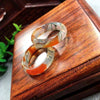 Two moss agate rings sitting on a wooden box surface