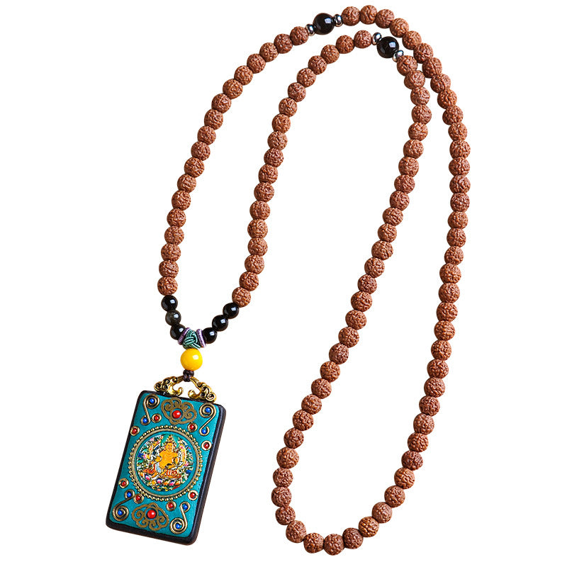 Close up of a black wooden pendant with gold deity figure and turquoise accents on a brown seed chain