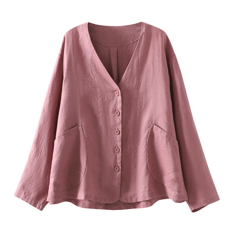 Pink cotton V-neck women's jacket hanging on a wooden hanger against a dark wood wall