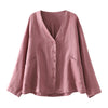 Pink cotton V-neck women's jacket hanging on a wooden hanger against a dark wood wall