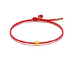 A red braided cord bracelet featuring a small round 999 gold bead.
