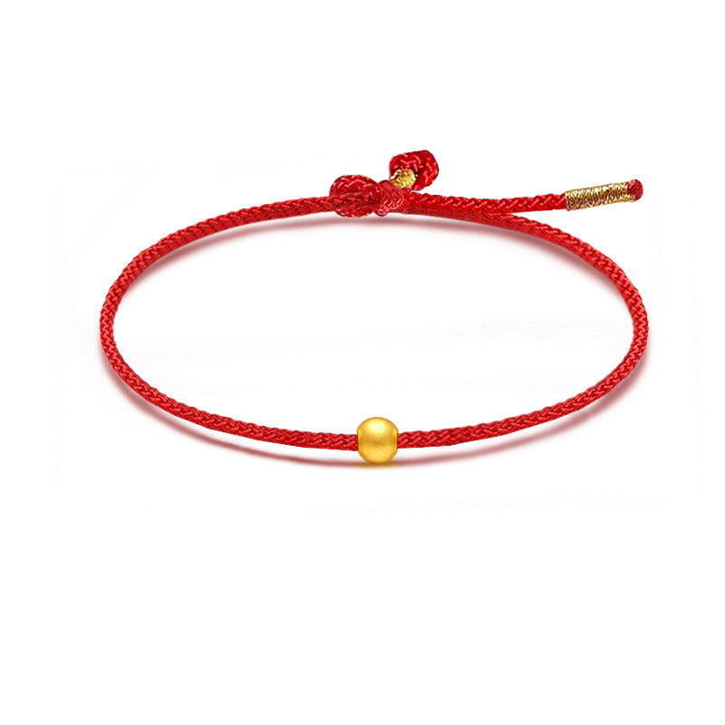 A red braided cord bracelet featuring a small round 999 gold bead.
