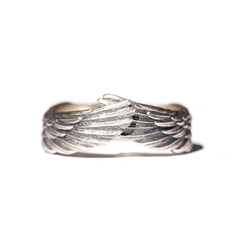 Close up of silver-tone adjustable ring with angel wing texture on white background