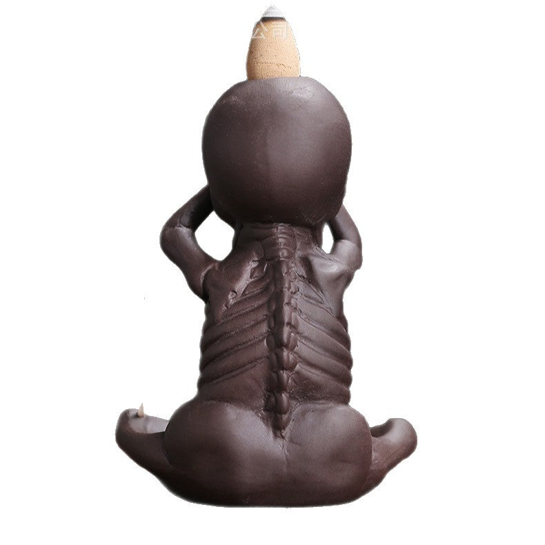 Back view of a brown skeleton-shaped backflow incense burner