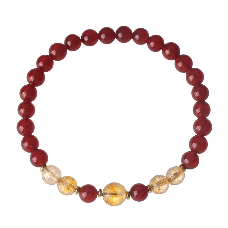 Close up of a red agate and yellow citrine beaded bracelet on a textured surface