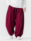 Man wearing maroon wide-leg harem pants with a white shirt