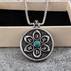 Round stainless steel pendant with six-syllable mantra petals and a blue turquoise center stone on a box chain