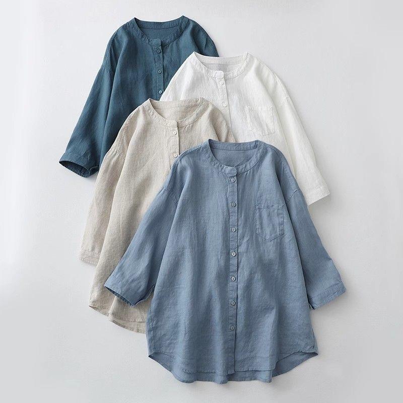 Four solid color shirts with round necks and buttons laid flat