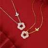 Close up of a silver necklace with a white jade flower pendant and a butterfly charm on a red background