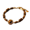 Close-up of a tiger eye bead bracelet with a gold-tone copper charm on a brown surface