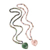 Two long beaded necklaces with large heart pendants in pink and green resting on wood