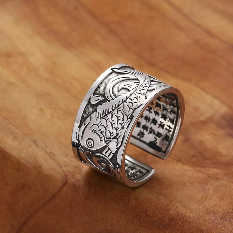 Close up of silver tone copper ring with carved koi fish and text
