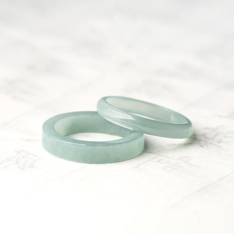 Two light blue natural jade rings resting on a white marble surface