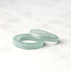 Two light blue natural jade rings resting on a white marble surface
