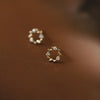 Close up of tiny gold-tone wreath stud earrings with stones on 925 silver posts