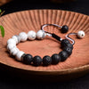 Black lava stone and white marble bead bracelet on a wooden plate