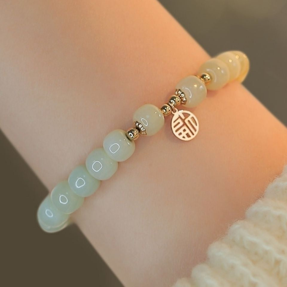 Gradient green bead bracelet with gold Fu charm on wrist