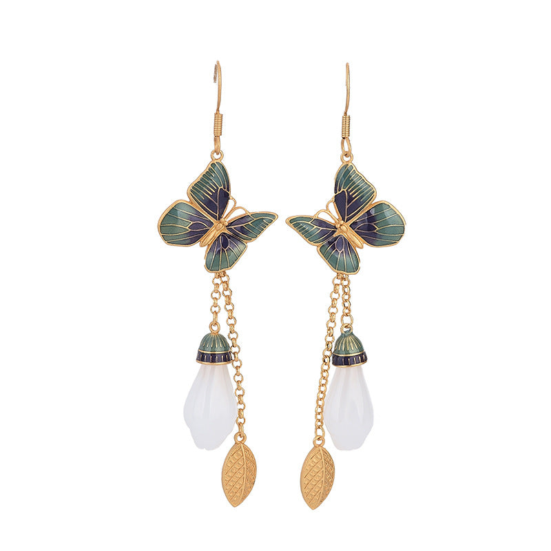 Gold tone butterfly earrings with white jade-like drop on a display stand