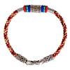 Close up view of a red and gold braided bracelet with a silver mantra cylinder