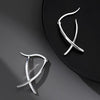 Silver-tone geometric cross hoop earrings on a dark background