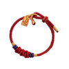 Red braided cord bracelet with gold fish charm and blue knot accents
