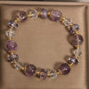 Close-up of a purple amethyst and clear crystal beaded bracelet on a beige surface