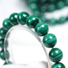 Close up of a green malachite beaded bracelet on a clear stand