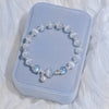 White cat eye stone bracelet with silver tone charms on a blue box