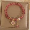 Pink strawberry quartz beaded bracelet with a gold-tone four-leaf clover charm and white pearl