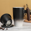 Black ceramic tea mug with white gradient and wooden handle next to coffee beans