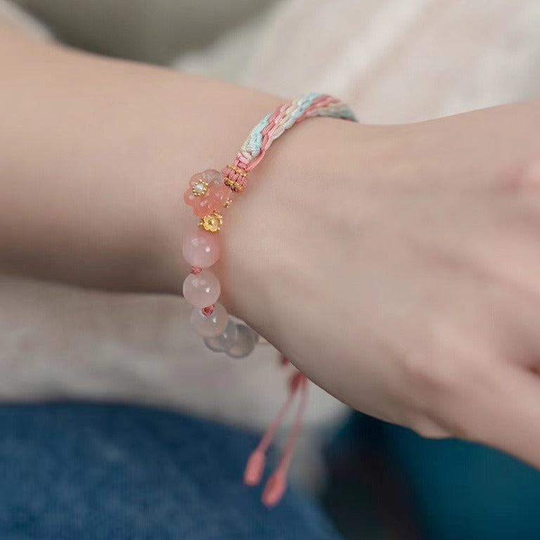Close-up of a wrist wearing a pink and white gradient agate bracelet with a woven knot.