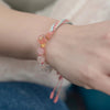 Close-up of a wrist wearing a pink and white gradient agate bracelet with a woven knot.