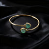 Gold-tone open cuff bracelet with two green aventurine stones on black fabric