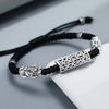 Close-up of a black braided bracelet with silver-tone Pixiu charms and a rectangular mantra bead