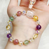 Close-up of a colorful beaded bracelet with purple, pink, green, and yellow stones held in hand.