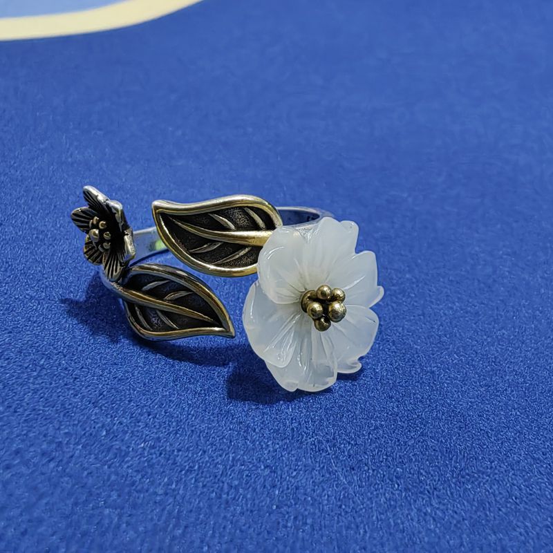 Close up of an adjustable ring with a white jade flower and bronze leaves