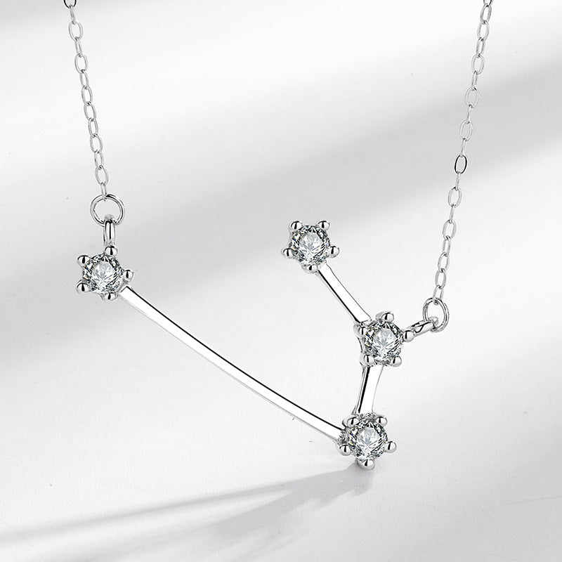 Close up view of a silver necklace with a constellation pendant design