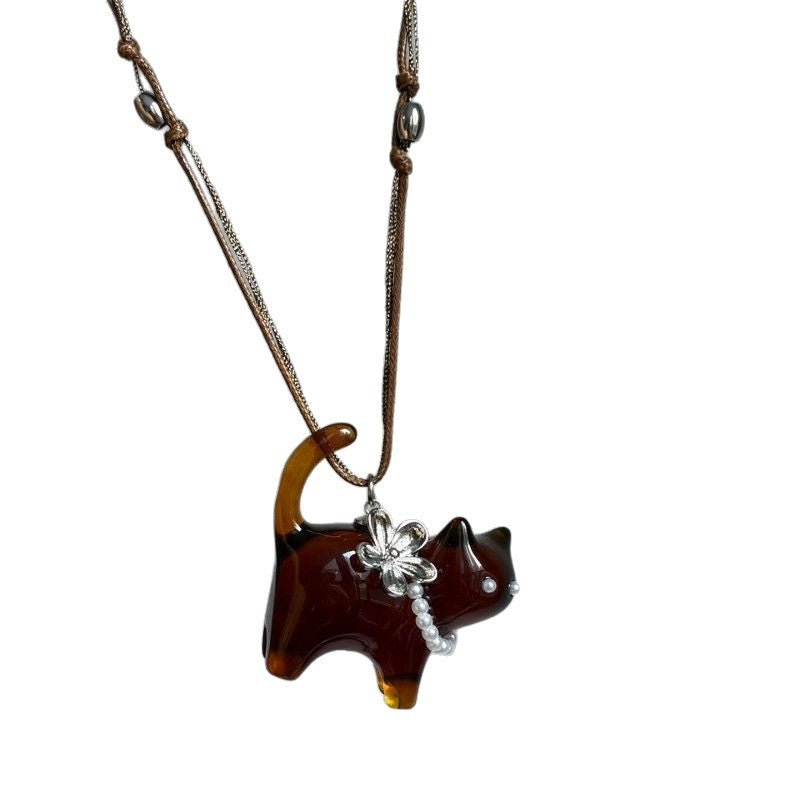 Brown and black resin cat pendant with a silver flower on a cord necklace