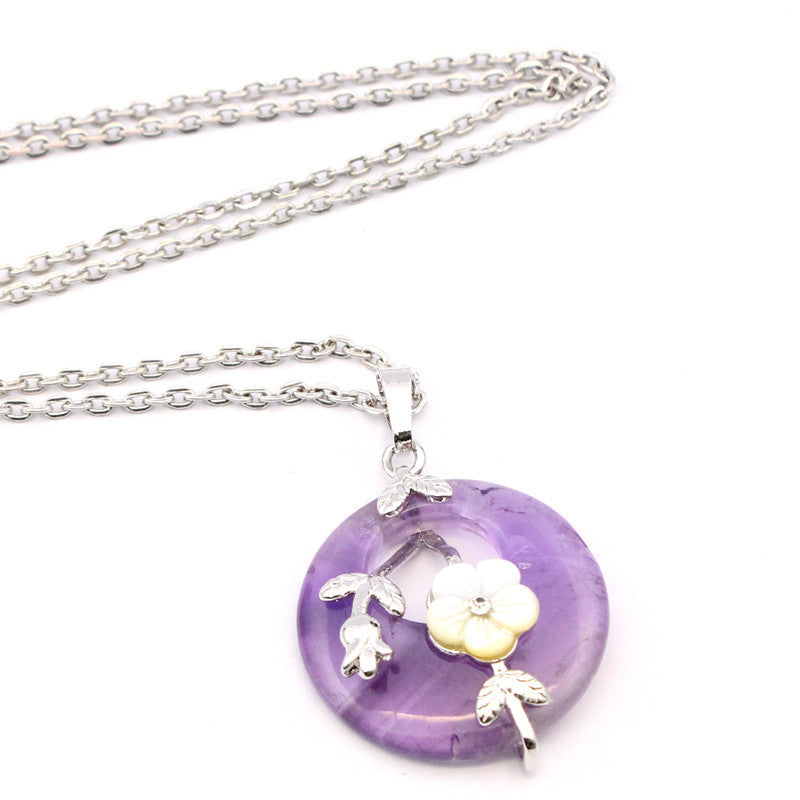 Purple amethyst donut pendant with a white flower and silver leaves on a chain