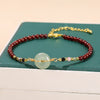 Close up of a red beaded bracelet with a light green peace buckle charm on a wrist