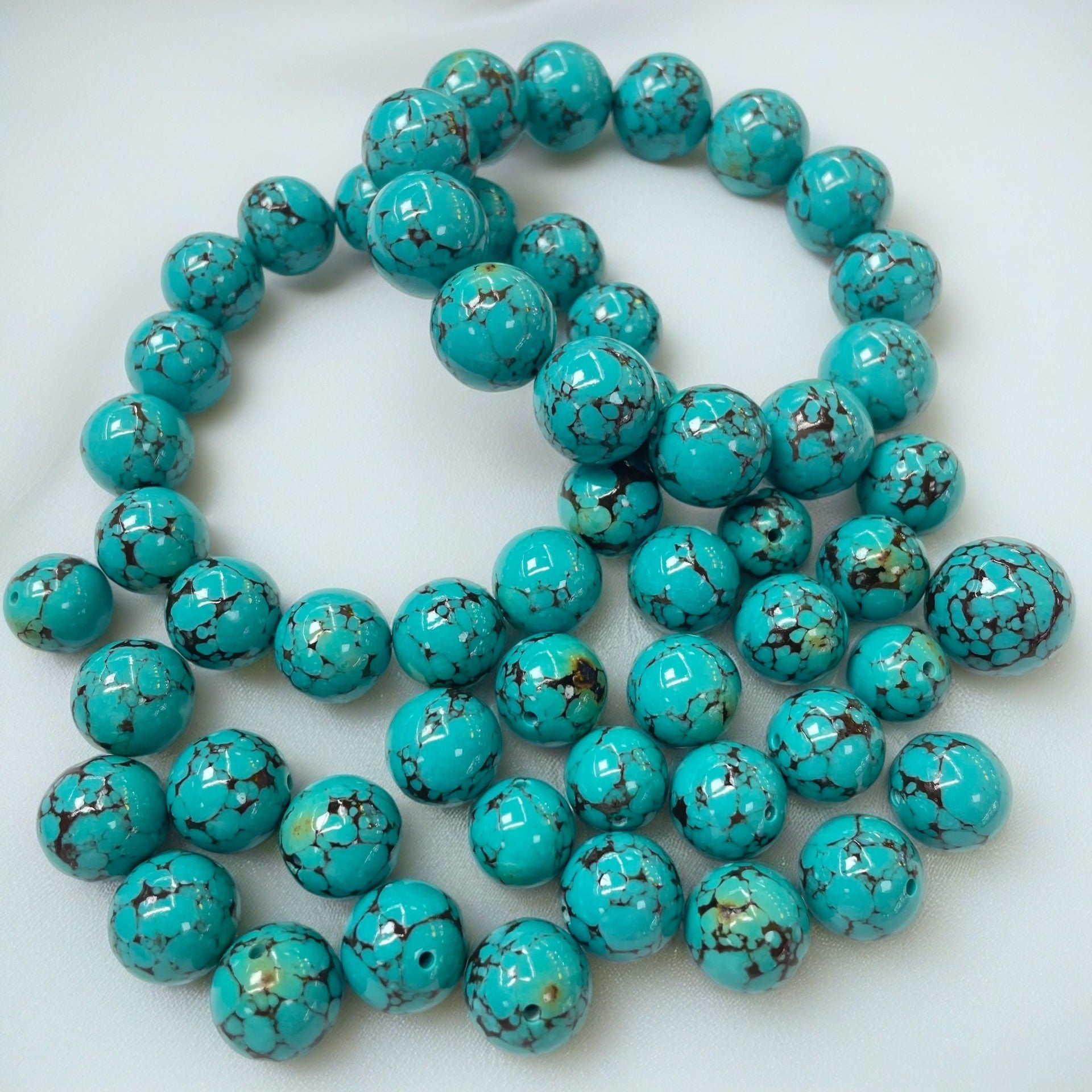 A collection of polished round turquoise beads with dark matrix lines
