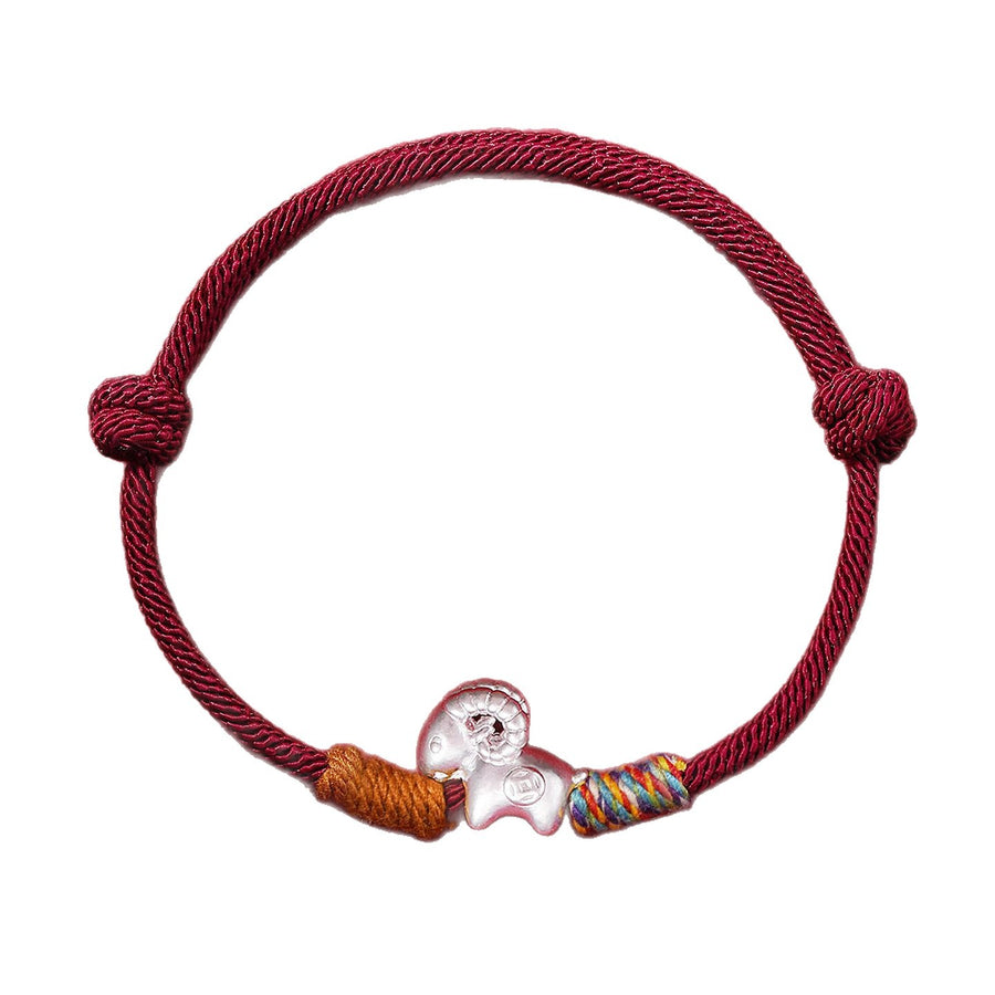 Model wearing a red string bracelet with a silver sheep charm