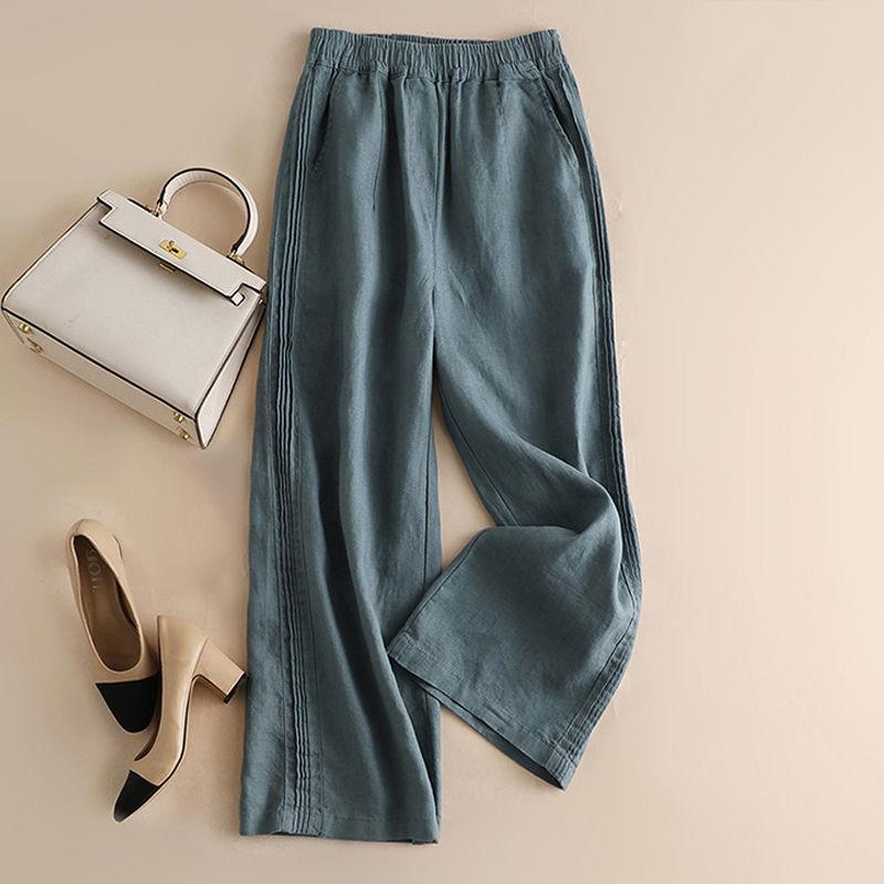 Flat lay of light beige wide leg pants with side pockets next to a handbag