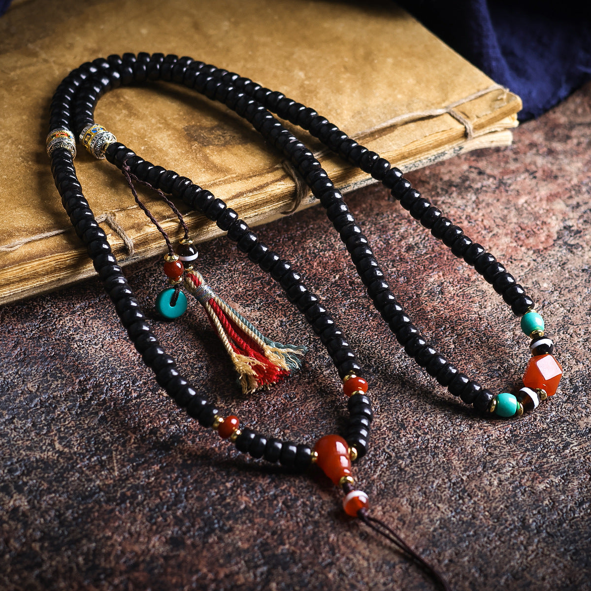 Black coconut shell bead necklace with red and turquoise accents on an old book
