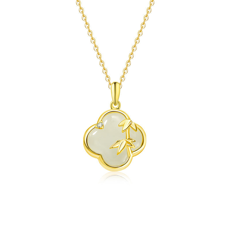 Close up of a silver four-leaf clover pendant with bamboo details and white jade on a chain.