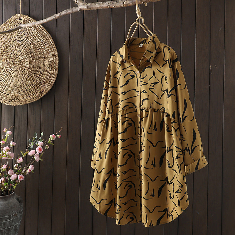 Yellow long sleeve printed shirt hanging on a wooden hanger against a dark wood wall