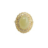 Close up view of an oval light green jade ring with a gold halo setting