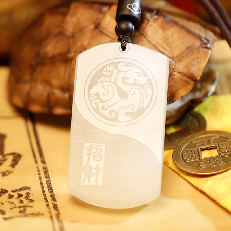 White jade pendant with Pixiu and Yin Yang carving on a dark cord